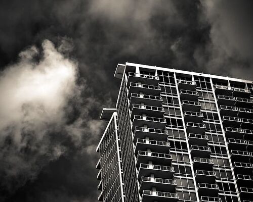 grayscale-photography-of-building-under-cloudy-sky